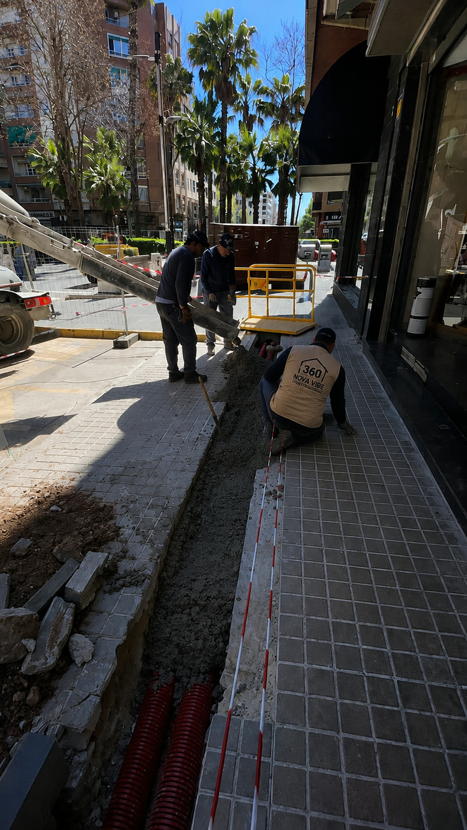 Vertido de hormigón en zanja de canalización sobre acera