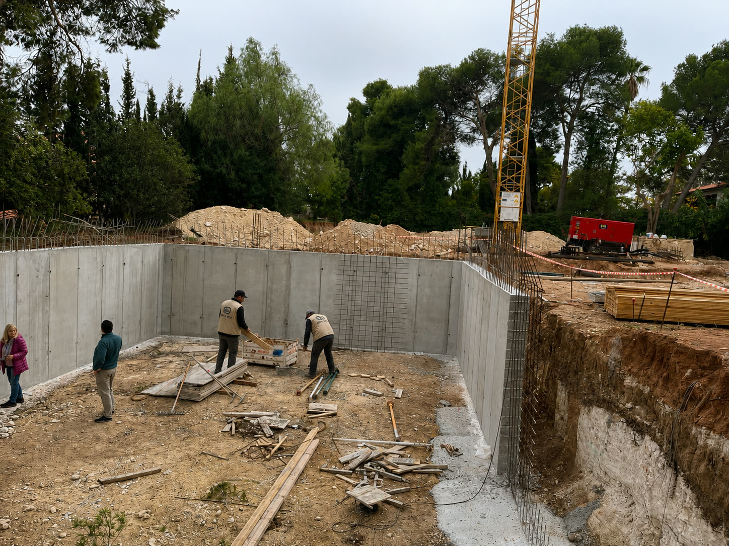 Muros de cimentación de hormigón y grúa torre en una obra de vivienda privada
