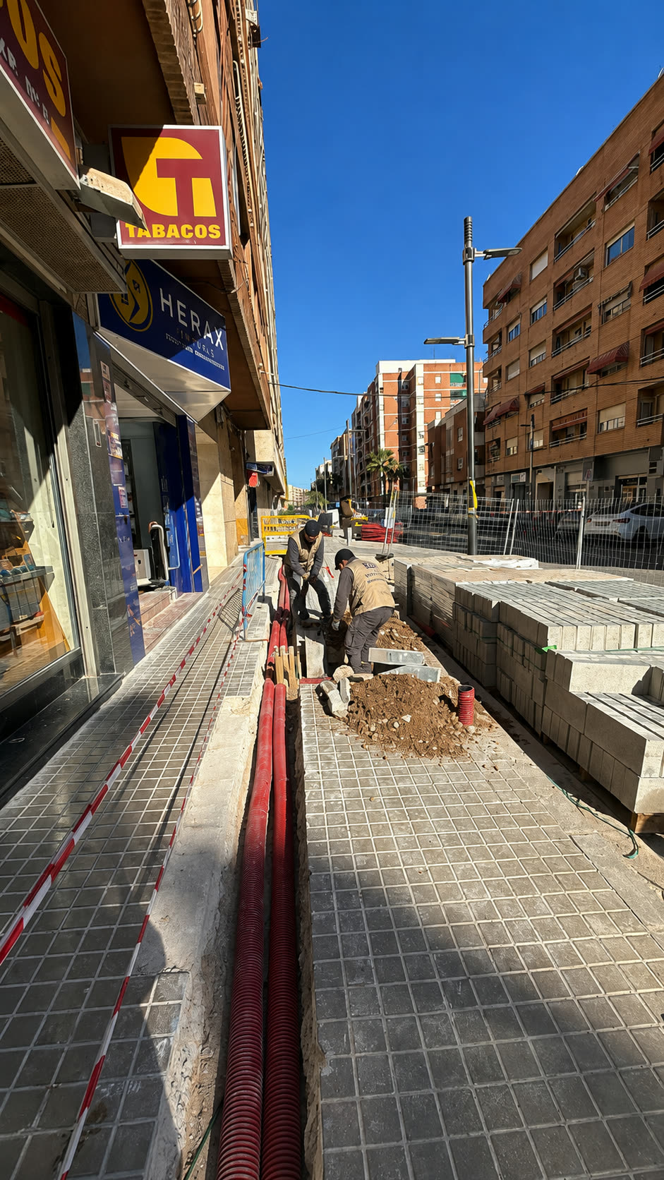 Operarios instalando tubería corrugada en zanja abierta en acera